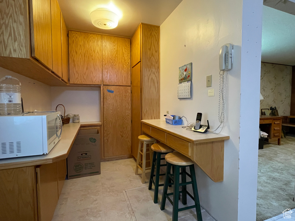 Kitchen with white microwave, light countertops, and brown cabinetry
