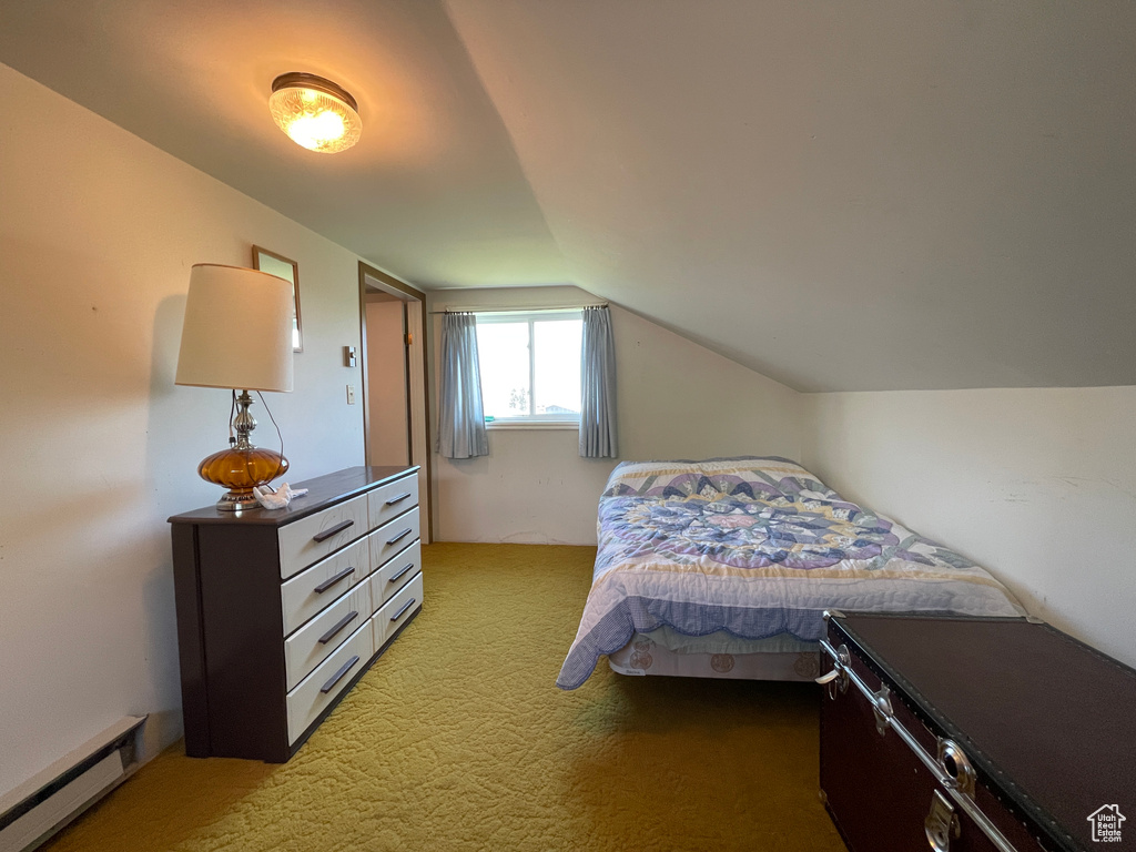 Bedroom featuring baseboard heating, light colored carpet, and vaulted ceiling