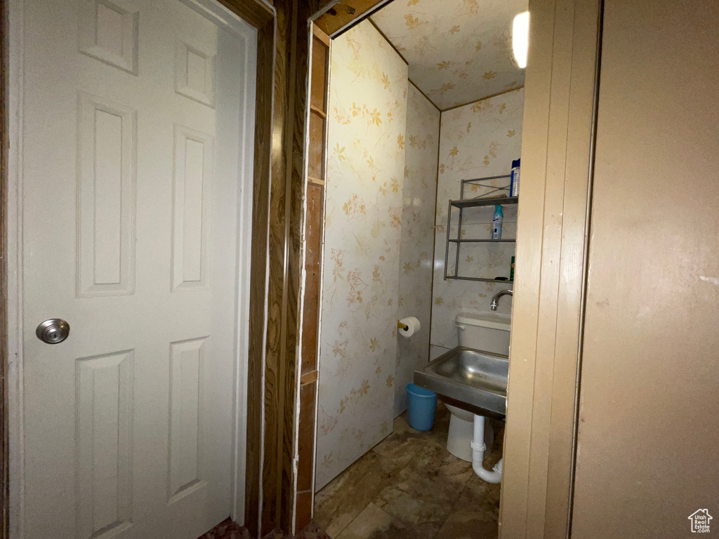 Bathroom featuring wallpapered walls and toilet