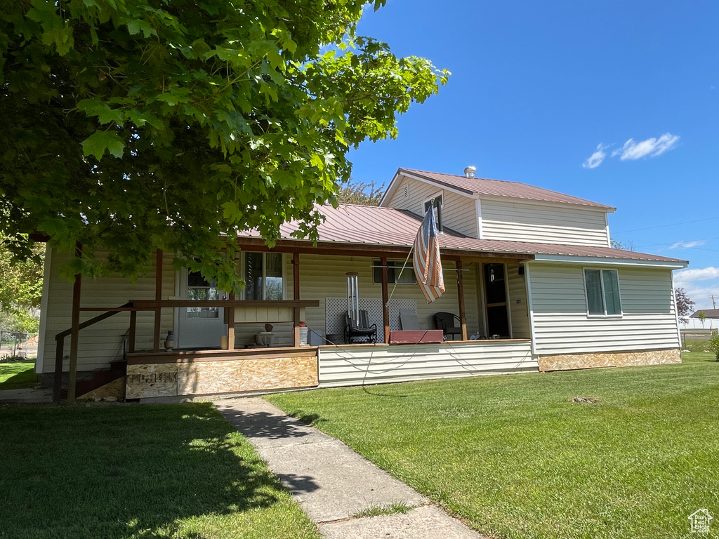 Rear view of property featuring a yard and metal roof