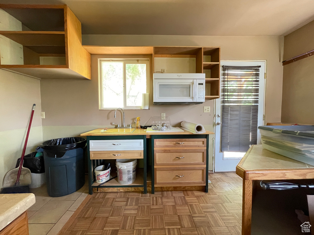 Kitchen featuring open shelves, white microwave, a sink, and light countertops