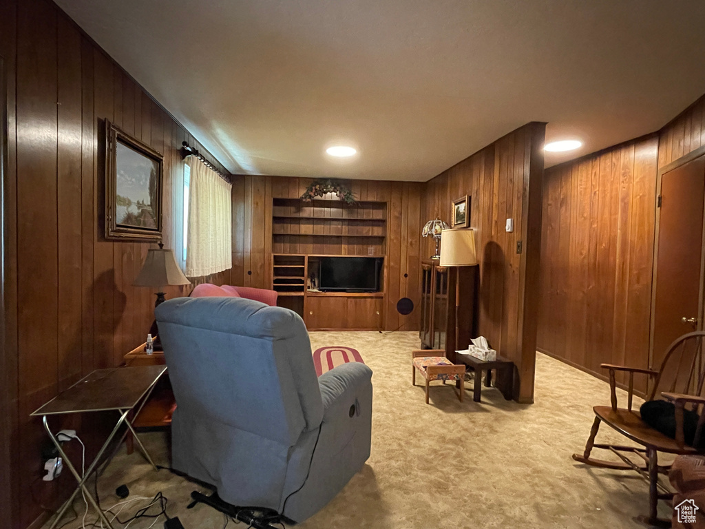 Living area with wooden walls, carpet floors, and a fireplace