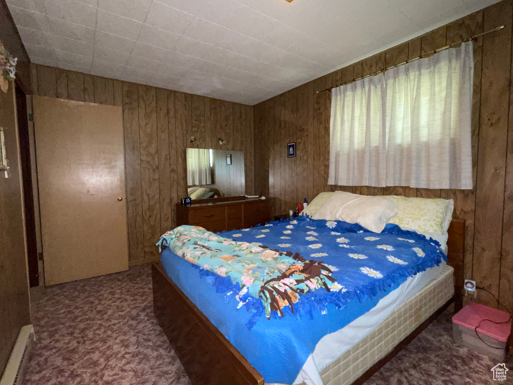 Carpeted bedroom with a baseboard radiator and wood walls