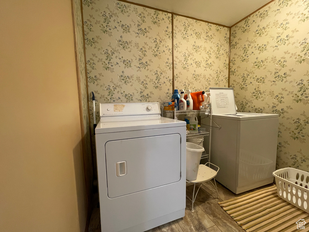 Laundry room featuring wallpapered walls, washer and clothes dryer, and wood finished floors