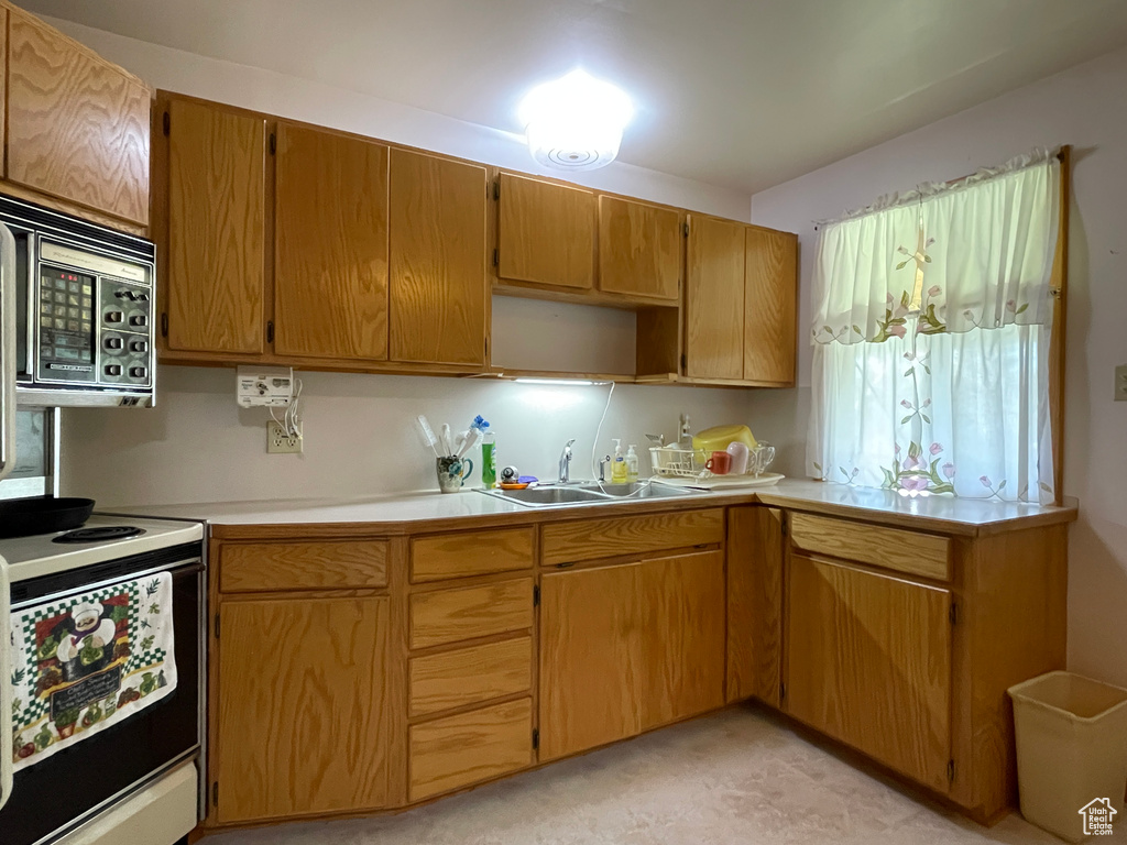 Kitchen featuring stainless steel microwave, electric range, a sink, and light countertops
