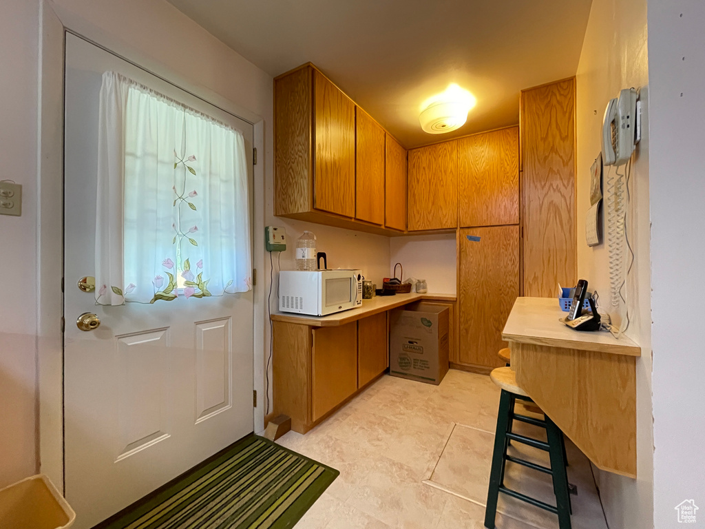 Kitchen featuring white microwave, brown cabinetry, and light countertops