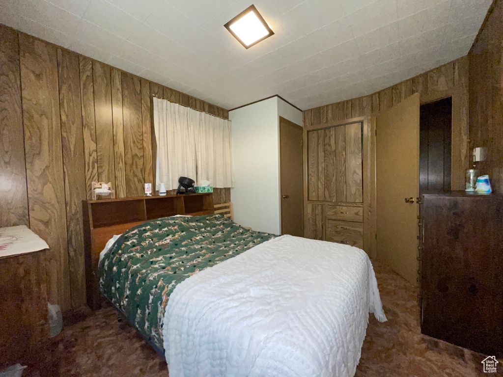 Carpeted bedroom featuring wooden walls
