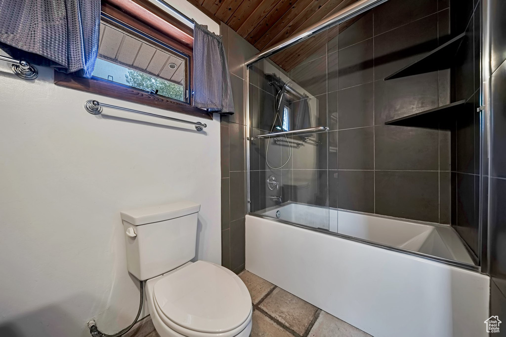 Full bath with toilet, combined bath / shower with glass door, wooden ceiling, and stone tile flooring