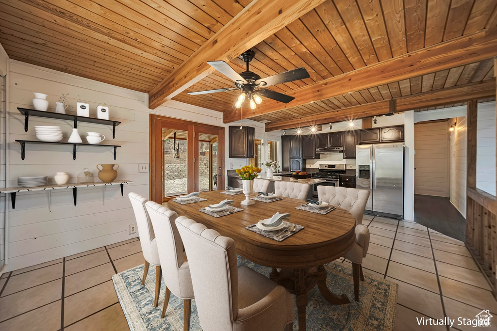 Dining area with light tile patterned flooring, wooden ceiling with exposed beams, wood walls, and ceiling fan