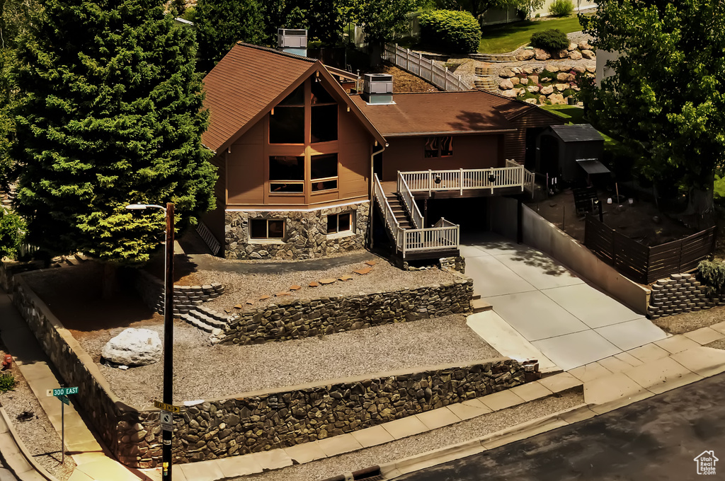 View of front of house featuring stone siding, concrete driveway, and stairway