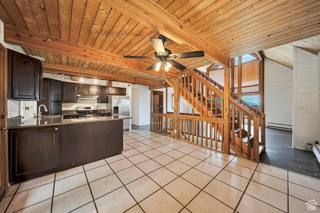 Kitchen with stainless steel appliances, wooden ceiling with exposed beams, baseboard heating, light tile patterned floors, and a peninsula
