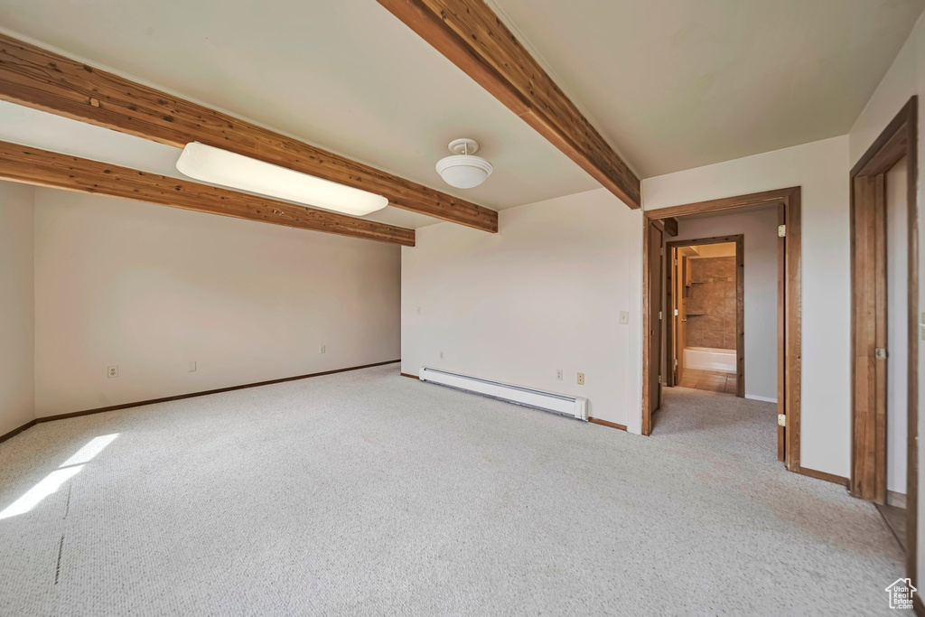 Spare room featuring a baseboard radiator, light colored carpet, baseboards, and beam ceiling