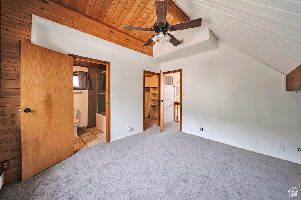 Unfurnished bedroom with carpet, wooden ceiling, a spacious closet, ensuite bath, and baseboards