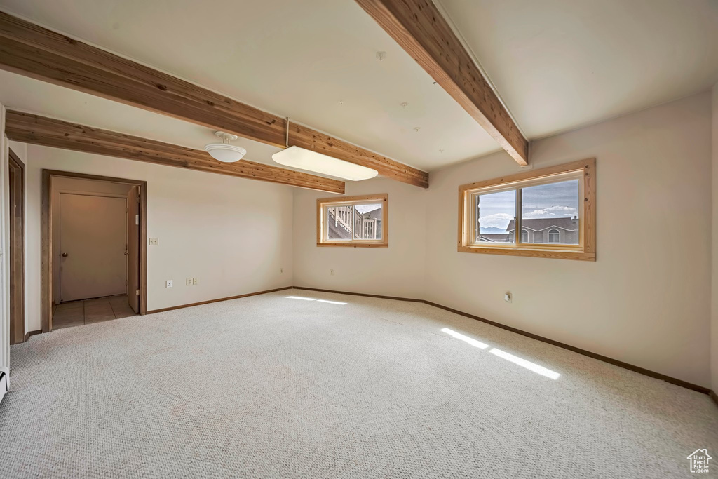 Unfurnished room featuring carpet, baseboards, and beam ceiling