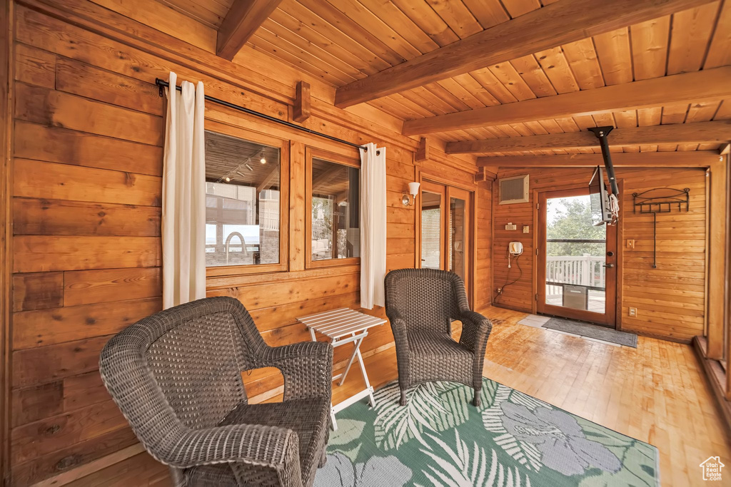 Living area featuring hardwood / wood-style flooring, wooden walls, and wood ceiling with exposed beams