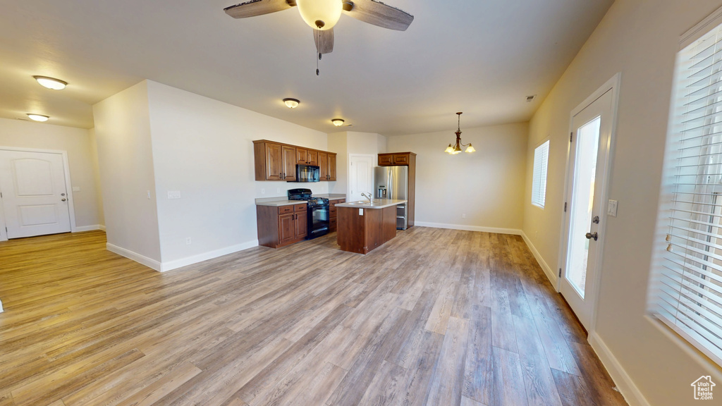 Kitchen featuring black appliances, open floor plan, brown cabinetry, a chandelier, and ceiling fan