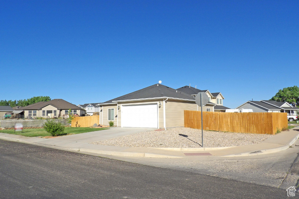 View of front of property with concrete driveway, an attached garage, and a residential view