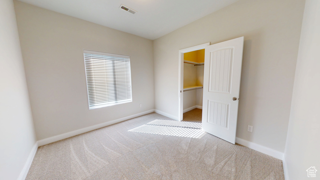 Unfurnished bedroom featuring carpet, a walk in closet, and baseboards
