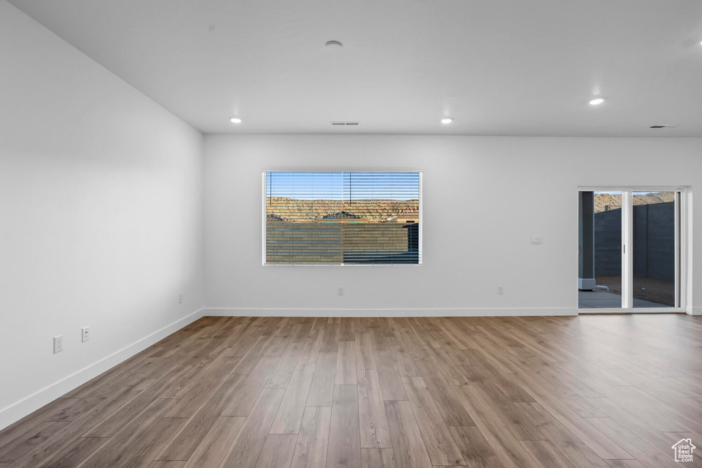 Empty room with wood finished floors, plenty of natural light, recessed lighting, and baseboards