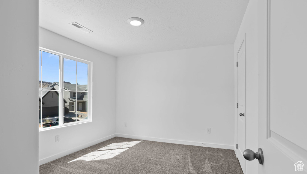 Carpeted spare room featuring baseboards and a textured ceiling