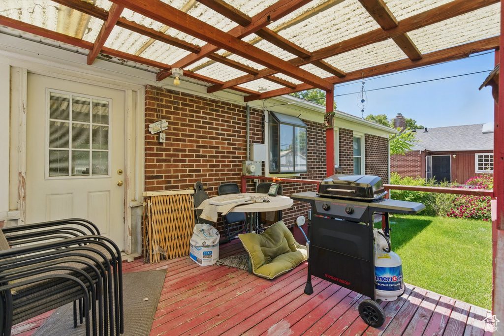 Wooden terrace featuring a grill, a pergola, and a yard