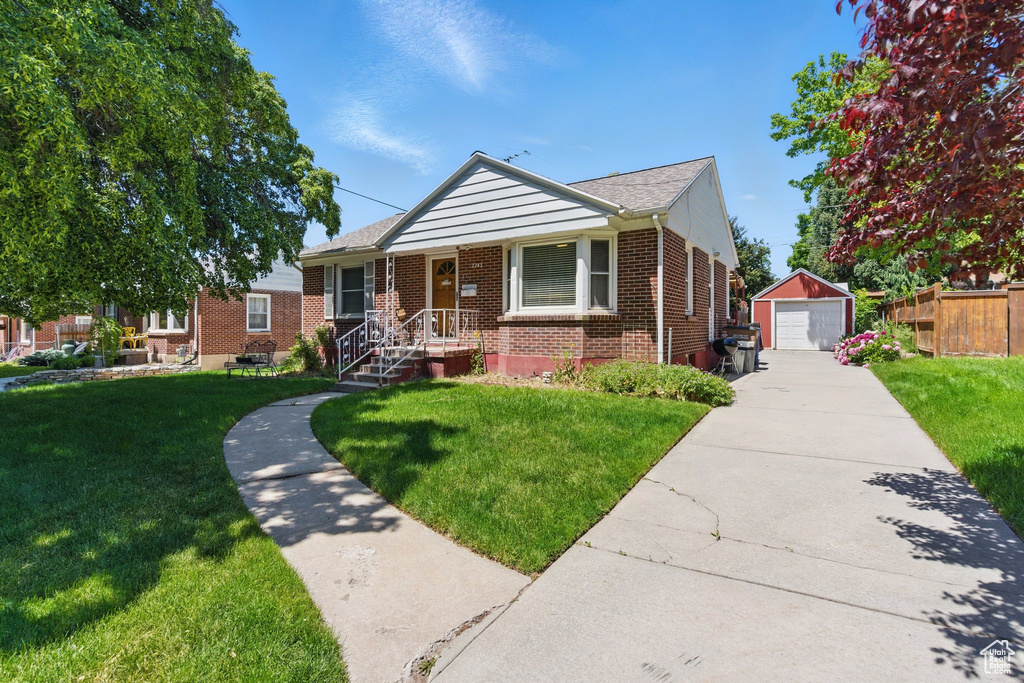 Bungalow featuring brick siding, an outdoor structure, a detached garage, and a front yard