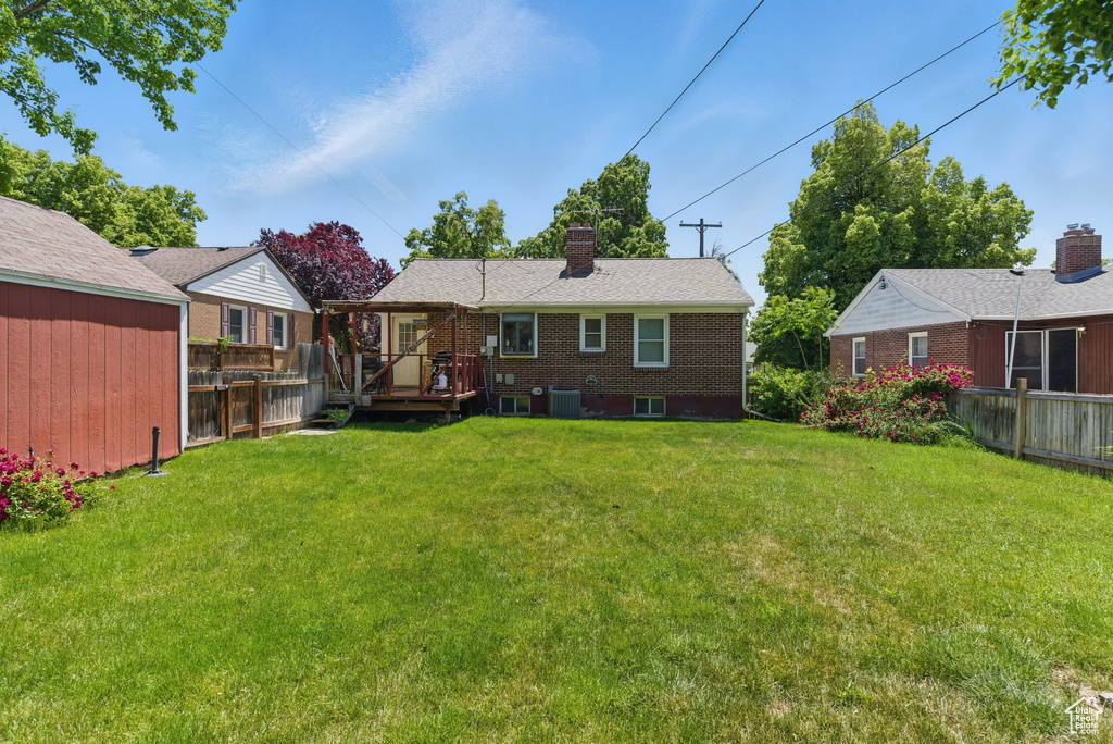 Rear view of house featuring central AC unit, a chimney, a deck, and brick siding
