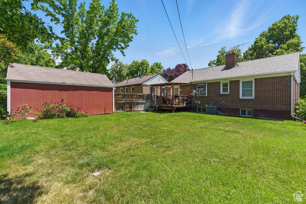 Back of house with a chimney, central AC, a deck, and brick siding