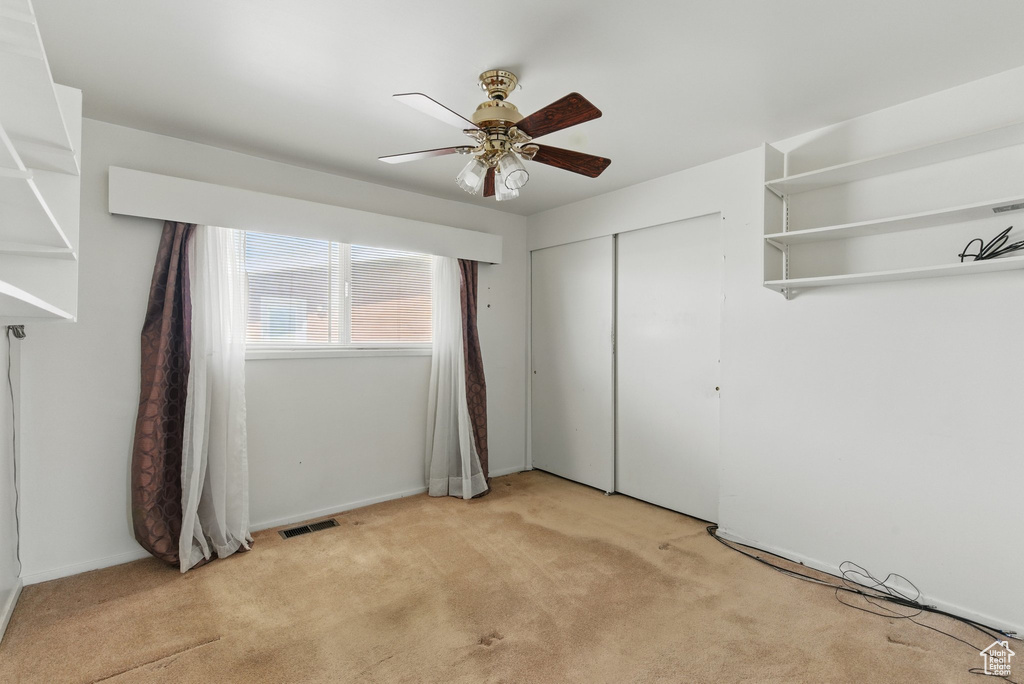 Empty room with light colored carpet and a ceiling fan