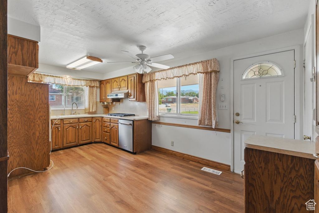Kitchen featuring appliances with stainless steel finishes, a sink, light countertops, ceiling fan, and under cabinet range hood