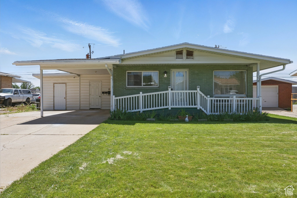 View of front of house featuring a front lawn, a carport, a porch, concrete driveway, and brick siding
