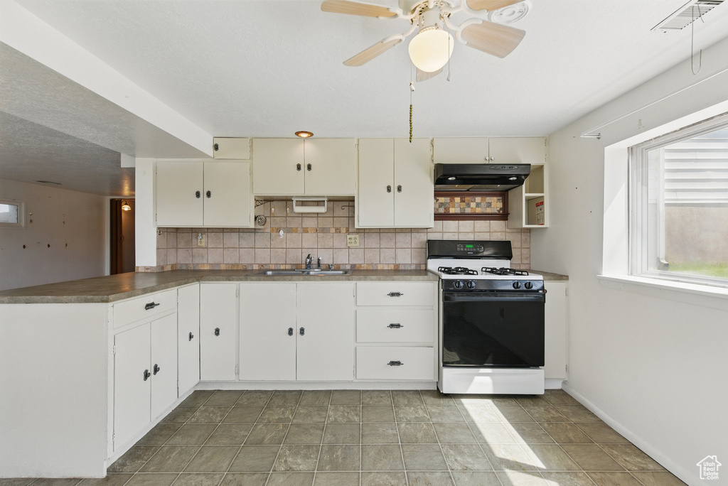 Kitchen with white range with gas cooktop, under cabinet range hood, a sink, backsplash, and a ceiling fan