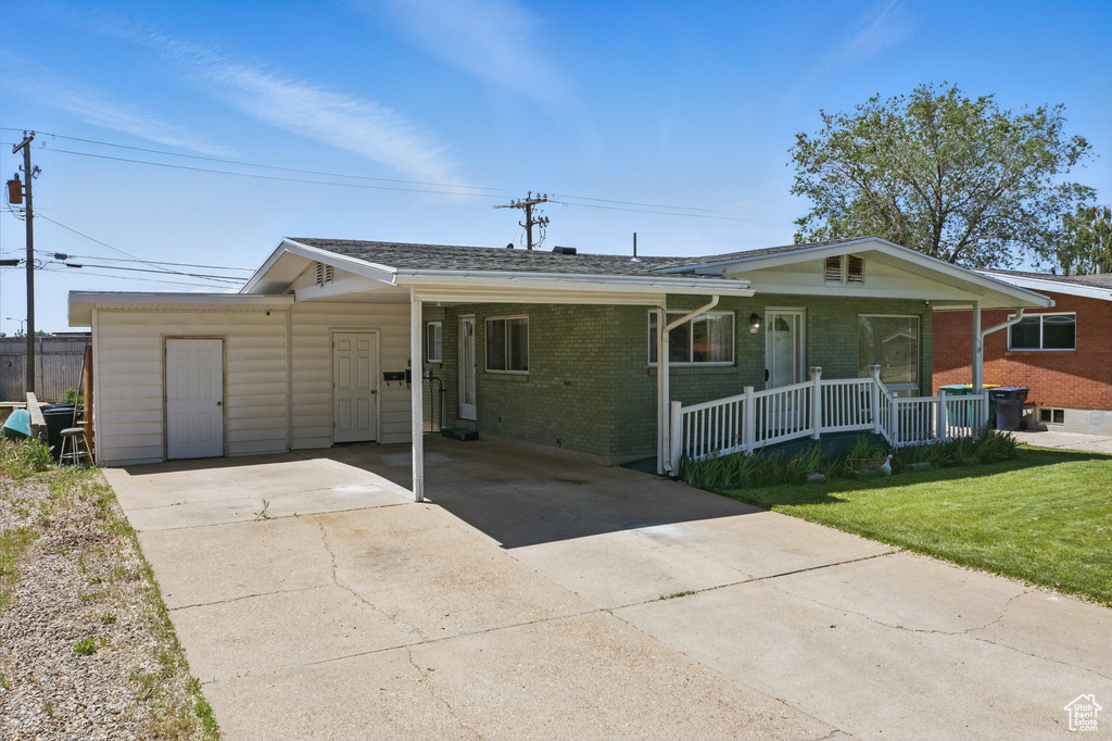 Ranch-style house featuring concrete driveway, covered porch, a front lawn, brick siding, and an attached carport