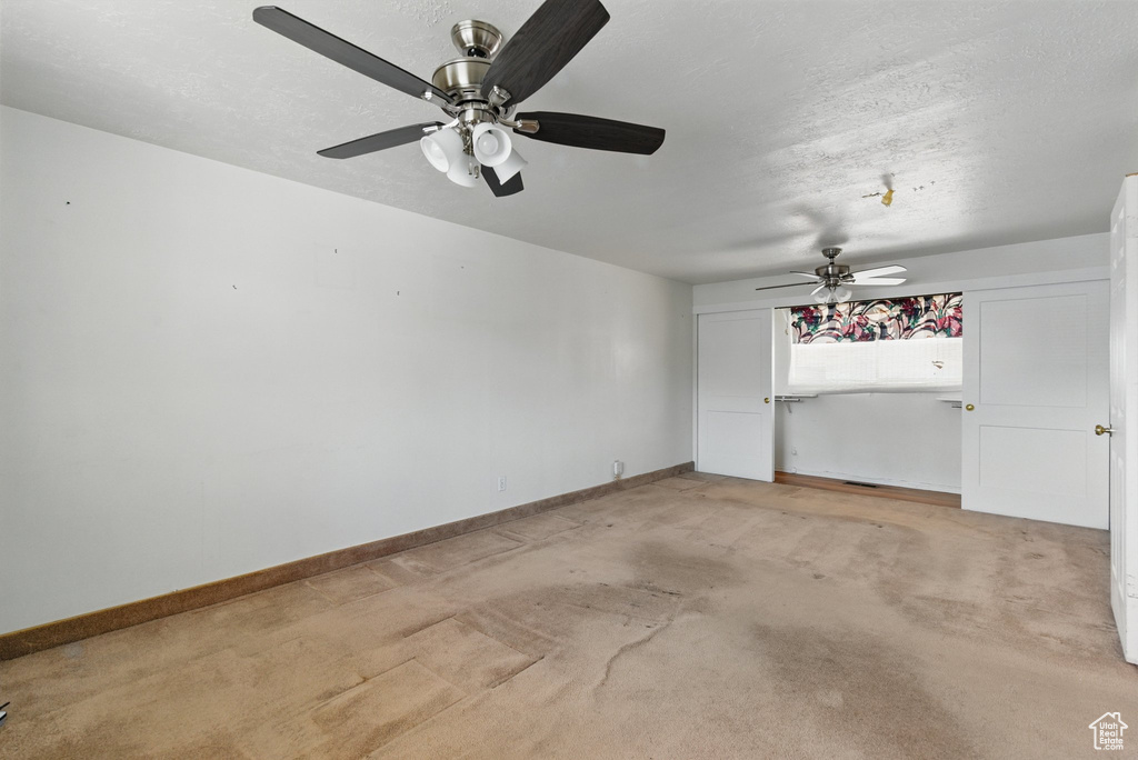 Unfurnished room featuring ceiling fan, light carpet, and baseboards