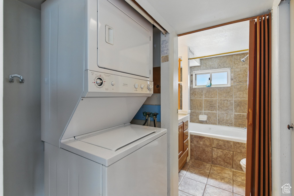 Laundry area featuring stacked washer and clothes dryer and light tile patterned flooring