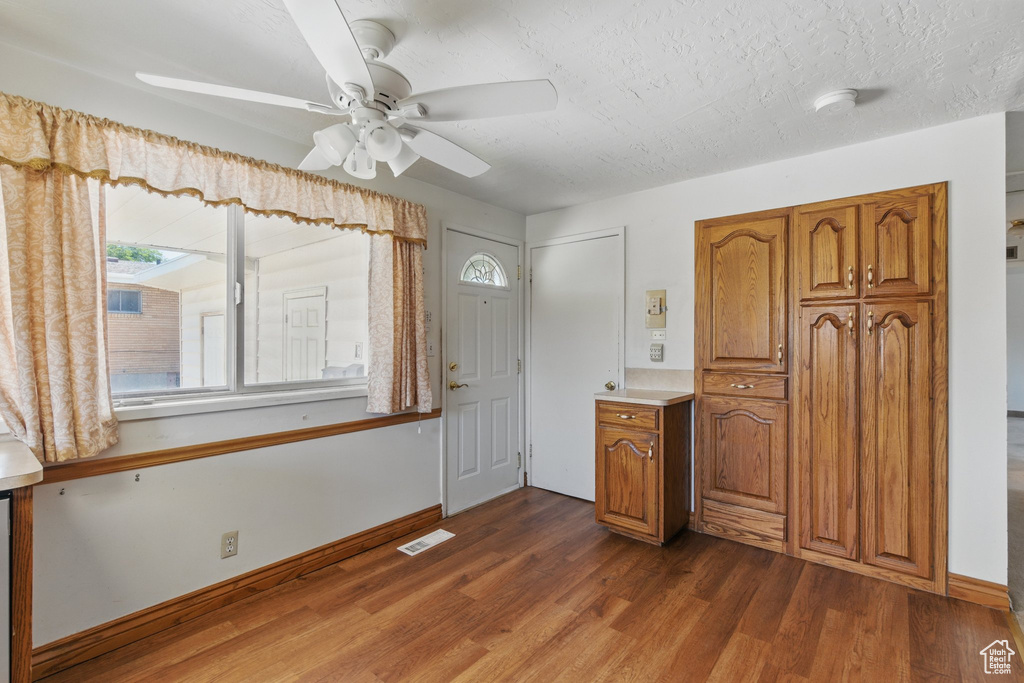 Entrance foyer with dark wood-style floors, healthy amount of natural light, ceiling fan, baseboards, and a textured ceiling