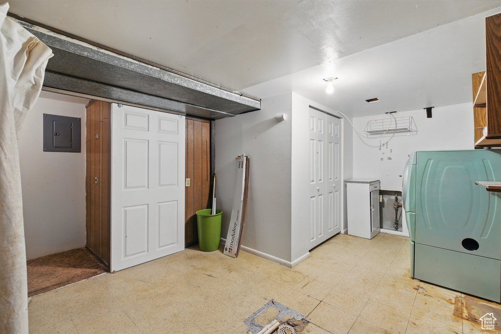 Finished basement featuring electric panel, light flooring, and washer / clothes dryer