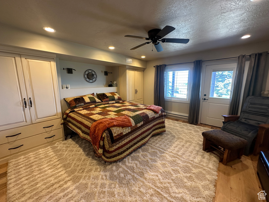 Bedroom with light wood-style flooring, recessed lighting, a ceiling fan, a textured ceiling, and baseboard heating