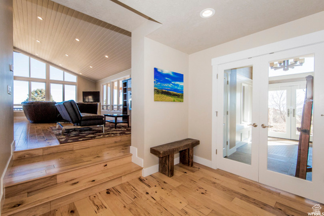 Hallway featuring french doors, wood-type flooring, lofted ceiling, recessed lighting, and baseboards