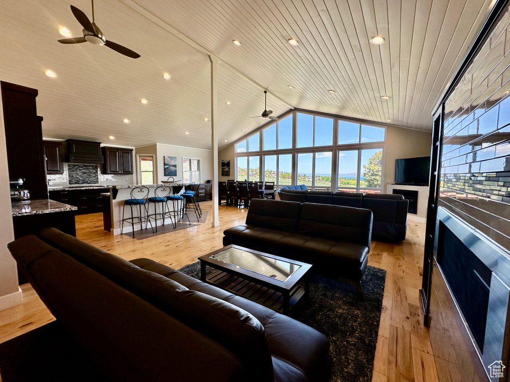 Living room with a ceiling fan, lofted ceiling, light wood-type flooring, recessed lighting, and wooden ceiling