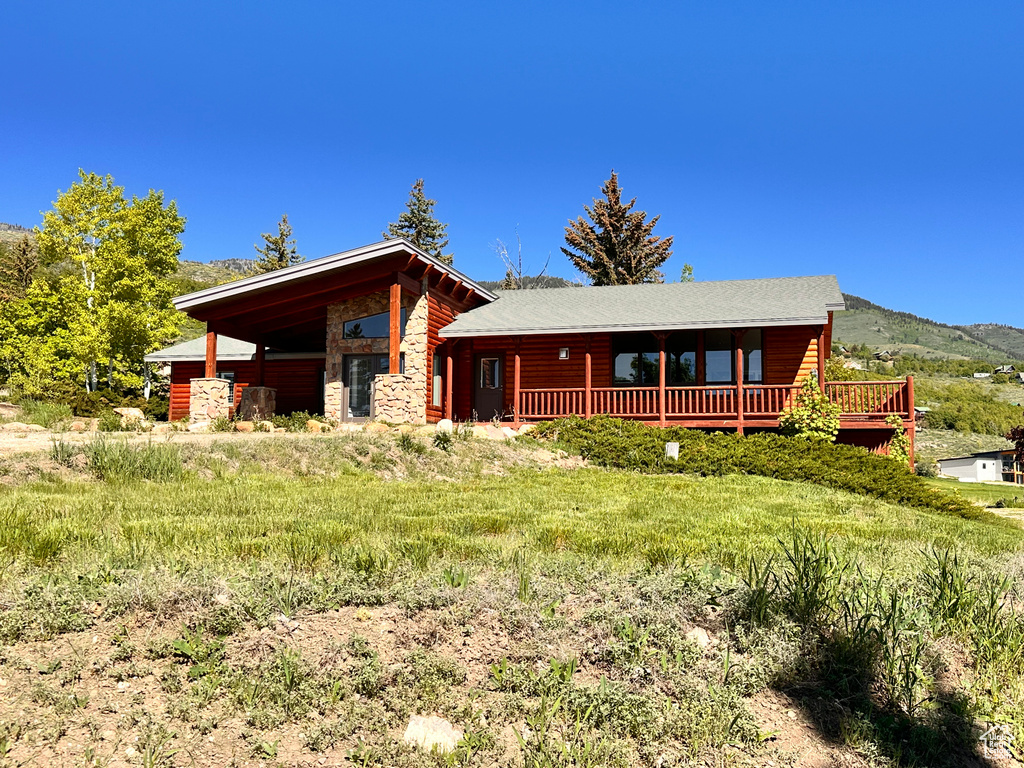 Log cabin featuring stone siding and a deck with mountain view