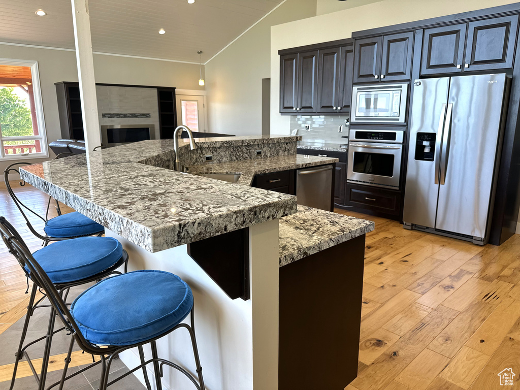 Kitchen featuring appliances with stainless steel finishes, a sink, crown molding, a kitchen breakfast bar, and recessed lighting