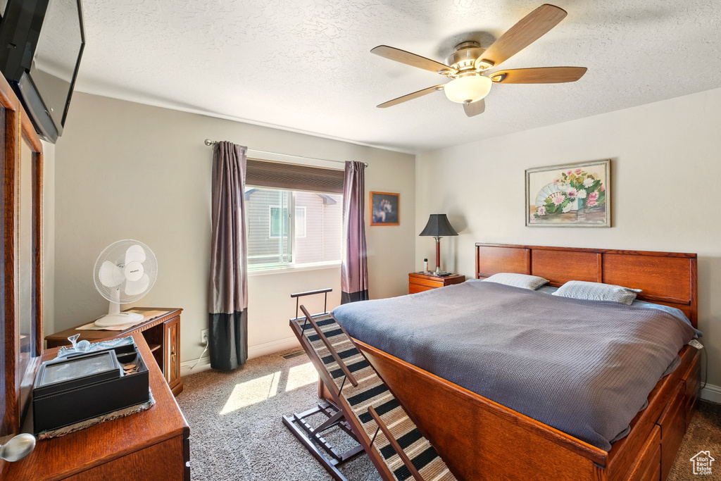 Bedroom featuring carpet floors, baseboards, a textured ceiling, and ceiling fan