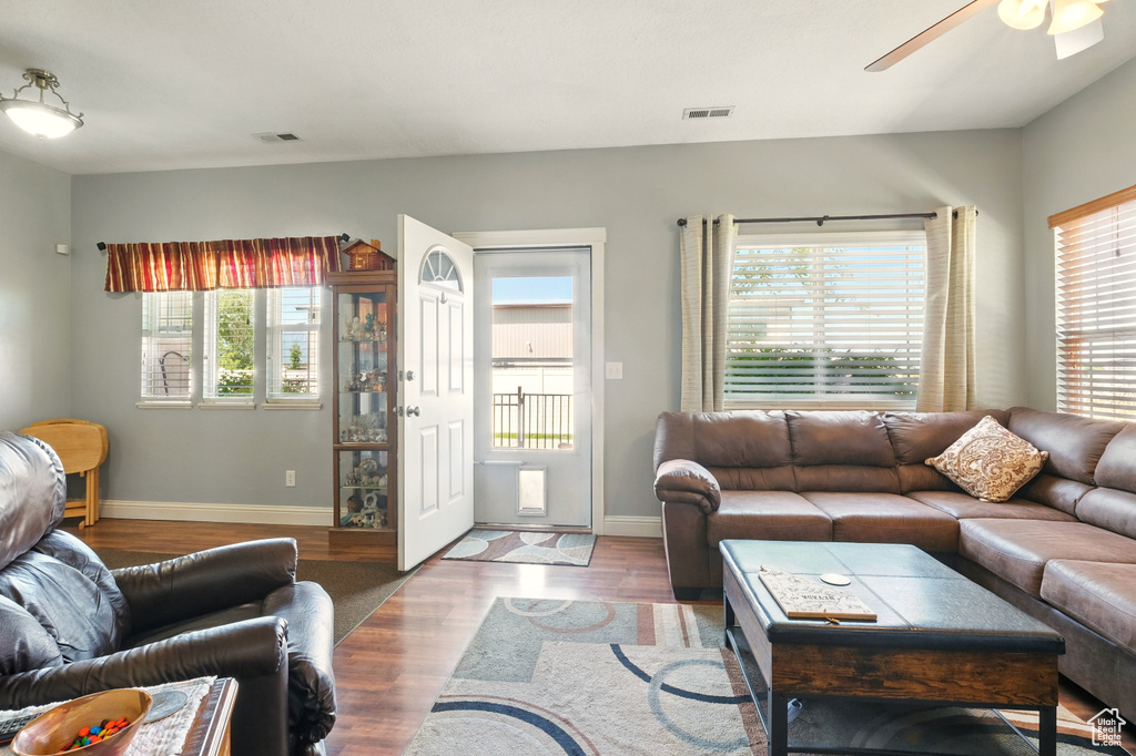 Living area with healthy amount of natural light, ceiling fan, and wood finished floors