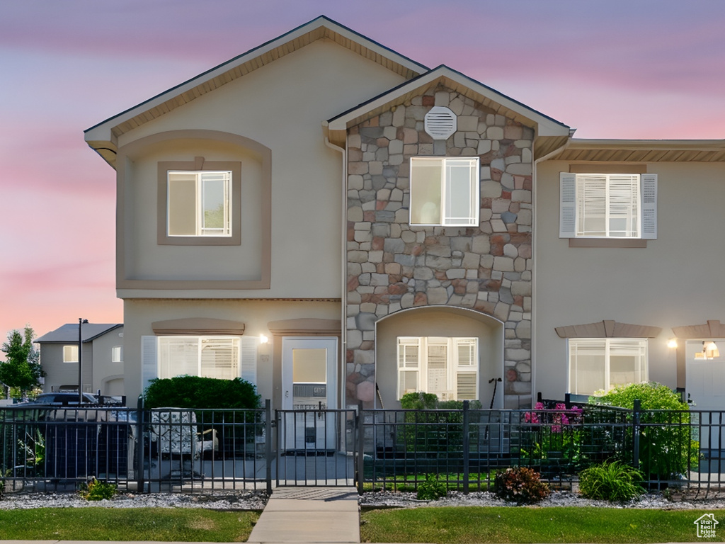 Townhome / multi-family property featuring stucco siding and stone siding