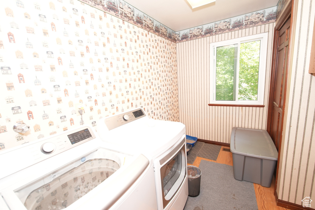 Laundry area featuring separate washer and dryer, wallpapered walls, and baseboards