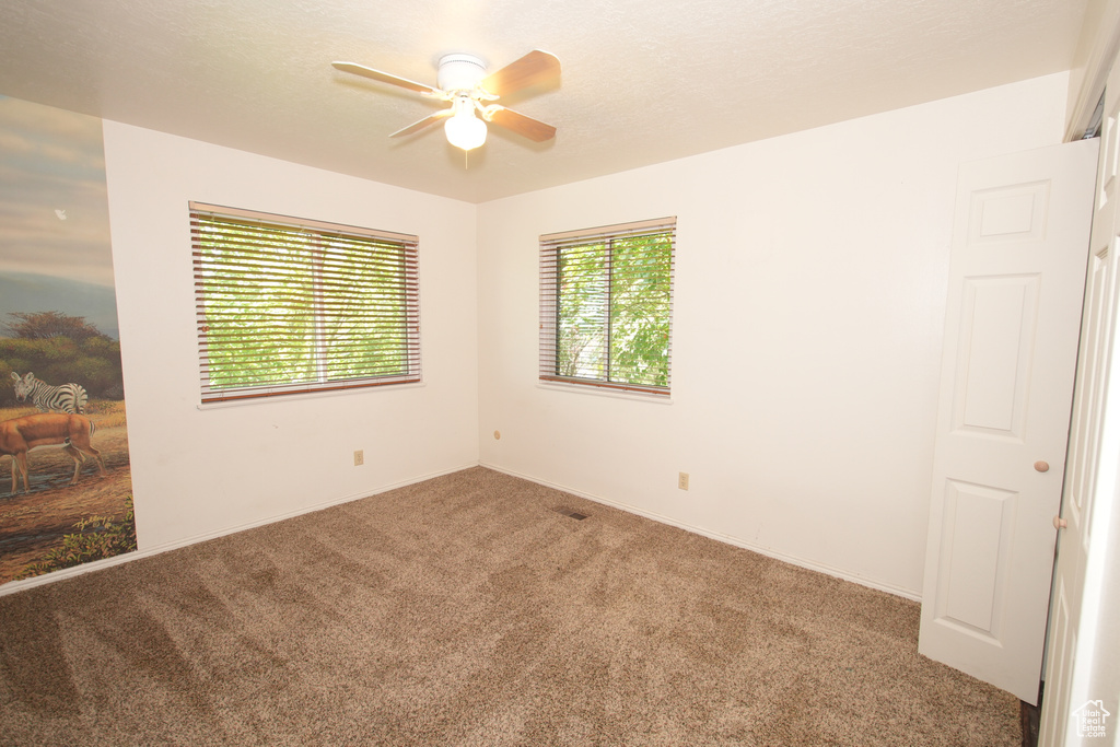 Carpeted spare room with a ceiling fan and baseboards