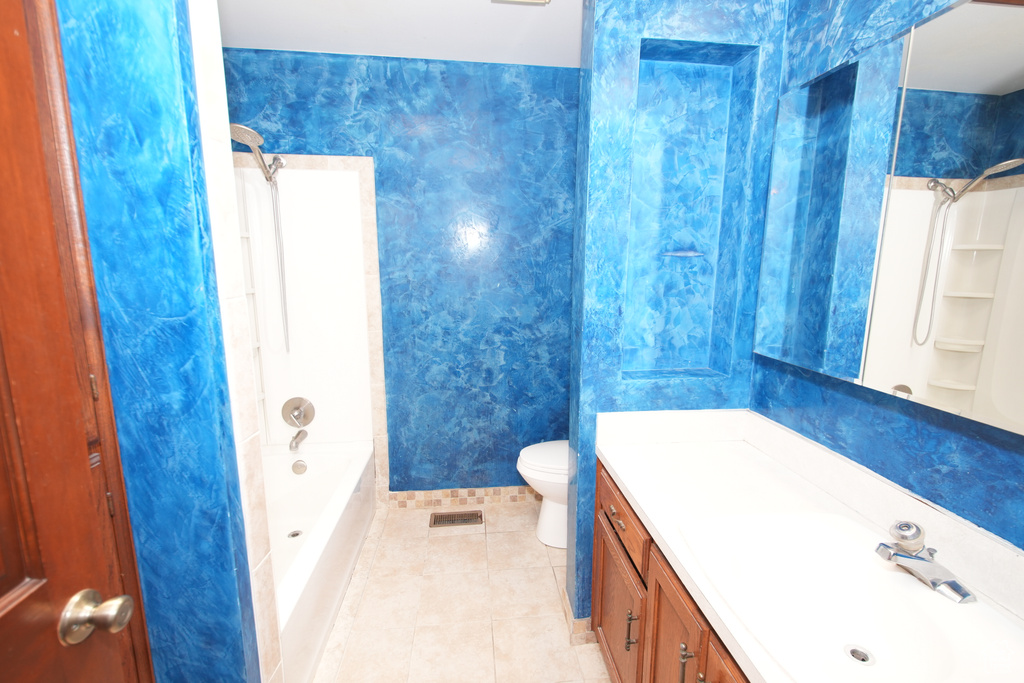 Full bath featuring vanity, toilet, tile patterned floors, shower / bathtub combination, and baseboards