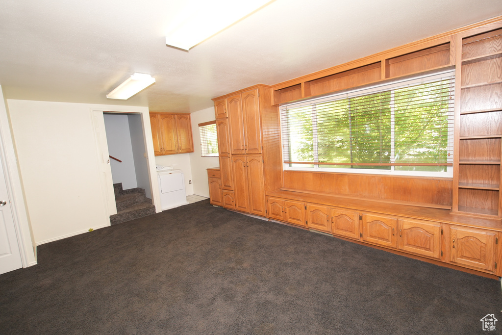 Unfurnished room featuring stairway and dark colored carpet