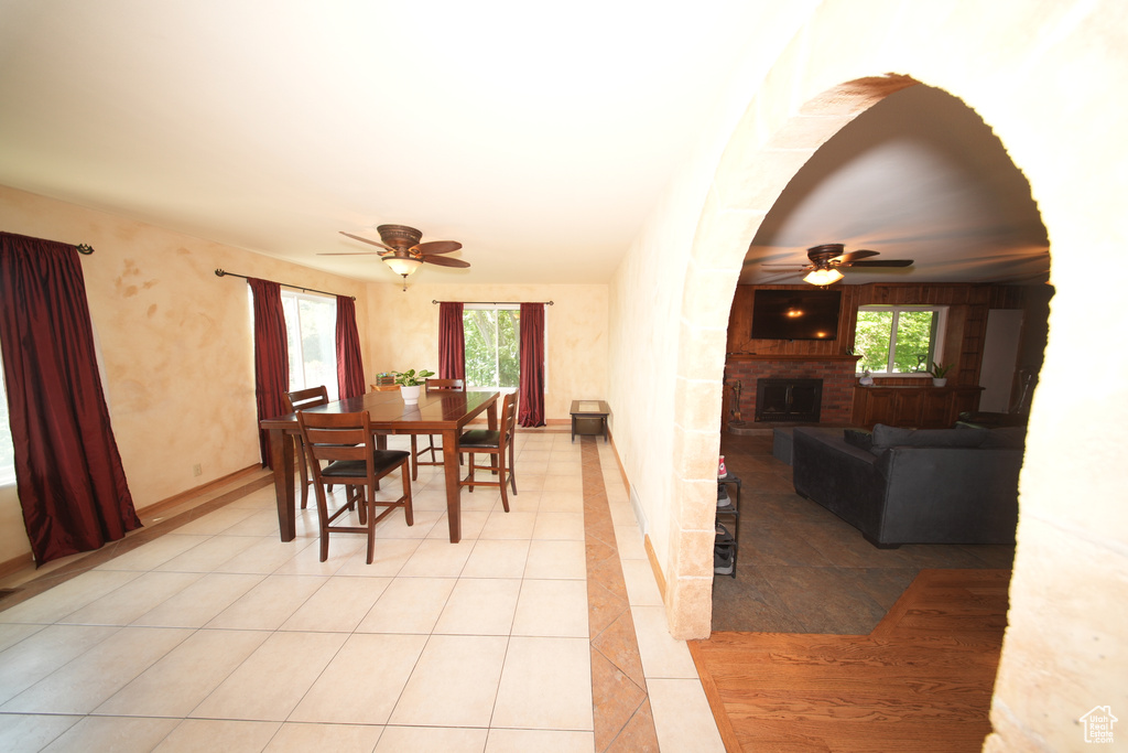 Dining space with a ceiling fan, a fireplace, plenty of natural light, and light tile patterned floors